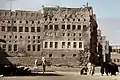 This photograph, taken in 1975, depicts one of the larger houses in Qatif Castle, with residents walking around it.