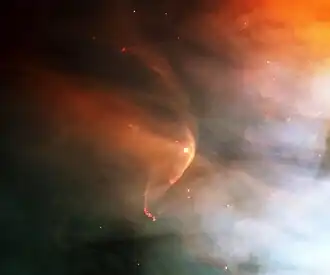Patchy orange and blue nebulosity against a black background, with a curved orange arc wrapping around a star at the center. (from Outer space)