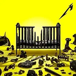 In a yellow room, there is a black broken crib with black broken objects on the floor. There is a stylized letter M from the Metallica logo in the top right corner.