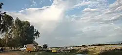 A vibrant rainbow over the Indus River near Hund, framed by lush greenery.