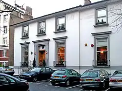A colour image of the façade of a brick building that is painted white