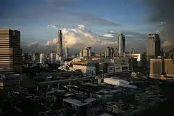 Many low-rise buildings in the foreground, with an elevated rail line and several medium box-saped buildings beyond; many tall buildings in the background