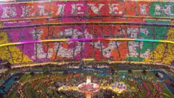 A set of rainbow-coloured placards read "Believe in Love" in a stadium