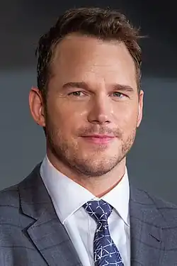 Pratt smiling at the camera while wearing a suit and tie.