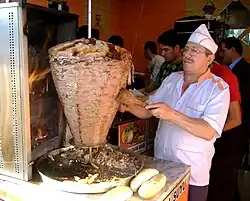 A cook slices ingredients into a skillet