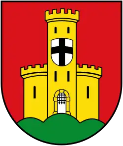 A shield with a red background, an orange castle in ruins, has a second shield of silver with a black cross.