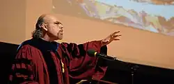 Carrasco delivers the Harvard Divinity School Convocation Address in front of an image of "Boxcar" by George Yepes.