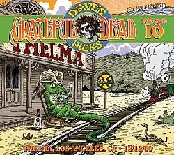 At a small train station in the desert, an alligator wearing a cowboy hat sits in a rocking chair and drinks a cup of tea, while a train approaches.