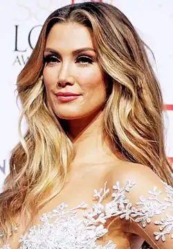 An ombre-haired woman in a dress smiles as she looks away from the camera