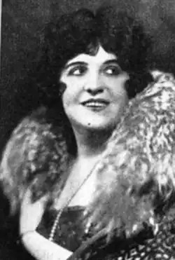 A smiling woman with light skin and dark hair, wearing a fur wrap