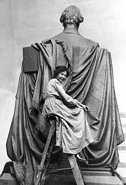 Elsie Ward sitting atop a ladder as she works on the backside of the Seated Lincoln.