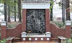 The memorial the end of a pathway featuring a brick monument with a bronze centerpiece
