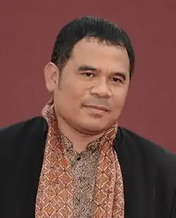 A man, on a red background, looking forward