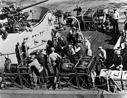 The U.S. Navy destroyer escort USS Inch (DE-146) with prisoners from German submarine U-490 (center, two wearing life vests, one in shirtsleeves) on her quarter deck, awaiting transfer to the escort carrier USS Croatan (CVE-25), 12 June 1944. U-490 had been sunk the previous night. Note the K-guns with fast-sinking streamlined depth charges mounted on the ship's side, 3/50 dual-purpose gun in upper left, photographer and guard with a Thompson submachine gun (both at right).