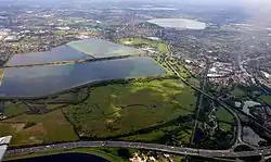 Image 14Seven reservoirs. View of four in Spelthorne with small lakes of lower elevation, from aggregate extraction, in the south of the borough to the right. Beyond three reservoirs in Elmbridge. The flattest areas of the far north of the county. Staines road and rail bridges span the Thames into Runnymede in the right of the photograph. (from Portal:Surrey/Selected pictures)