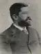 A black-and-white photograph of a man in a suit with a tie