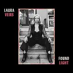 A black-and-white photo of Veirs seated on stairs