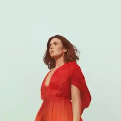 Image of a brunette woman in a red dress against a blue sky