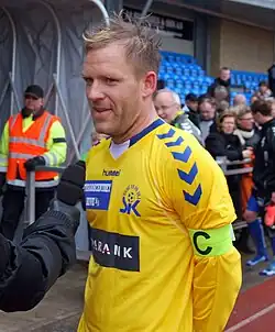 Footballer in a yellow jersey is being interviewed
