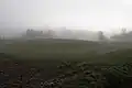 A low earth mound with ditch shrouded in mist