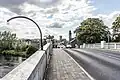 a view across a humpback road bridge, with a city in the background