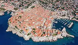 A view of Dubrovnik from the coast, showing defensive walls and a marina