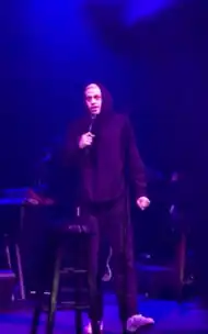 Davidson standing onstage with a microphone