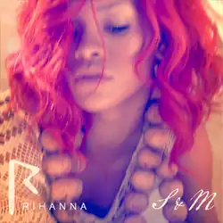 A close-up shot of a woman with red hair and her eyes closed. She is wearing a chunky necklace and a beige top.