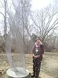 Artist Susan Mohl Powers standing by her perforated metal sculpture, "Dancing Galaxy"