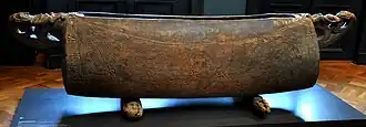 A garamut with geometric carvings in the central portion and handles carved with human figures