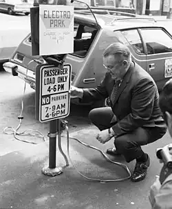 Gordon Vickery squats to examine a prototype electric car in 1973