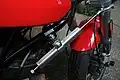 An aftermarket longitudinal linear motorcycle steering damper attached below the lower triple clamp