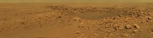 Figure 10. Concepcion Crater on Meridiani Planum. It is very young (~100,000 years old). It is not on the list of officially named craters; however, it was featured in Golombek et al 2014 a study of erosion at Meridiani Planum. The damage to the plain's sediments caused by the impact of the crater-forming meteorite aids in converting sediment embedded spherules into loose surface blueberries. This photograph is helpful for understanding the erosional processes that create the soils and loose blueberries (discussed below in a whole sub-section). A field of plain's ripples fills out the background - such background views are common at Meridiani. Image taken on Sol 2140 (2010-01-10).