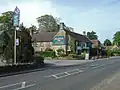 Building with pub sign saying the Sparkford Inn with car park and road in the foreground.