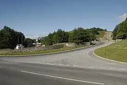 A road junction with limestone walls; a terminal railway is on the left beyond and the quarry entrance on the right