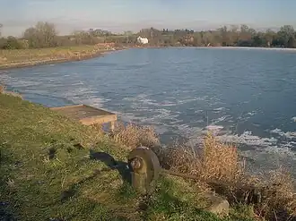A frozen lake with wooden fishing platforms dotted around the shoreline