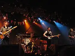 The Killers performing onstage playing and singing into a microphone
