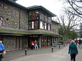 Modern stone-faced theatre with a lake in the background